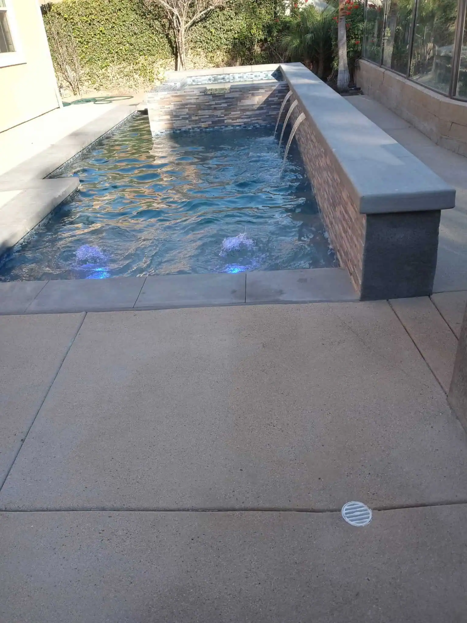 Custom concrete pool with water features and sleek design for backyard luxury.