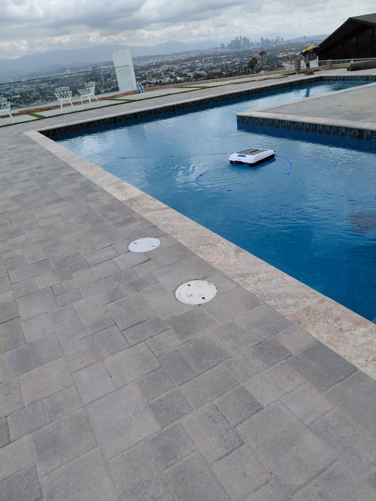 Rooftop pool with concrete deck and automated cleaning robot, offering a stylish and functional outd.