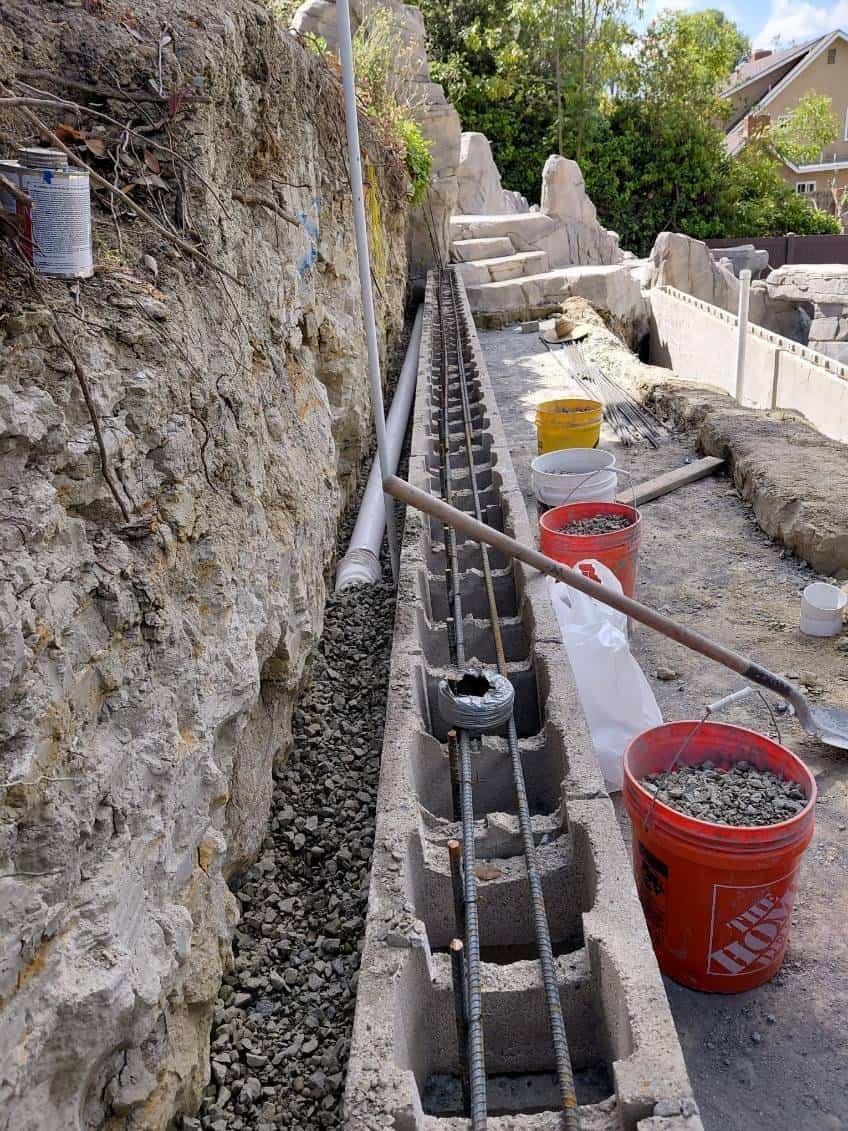 Rebar and concrete work for retaining wall installation at a construction site.